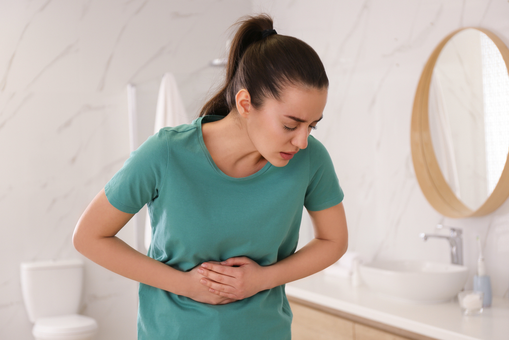 Young,Woman,Suffering,From,Stomach,Ache,In,Bathroom